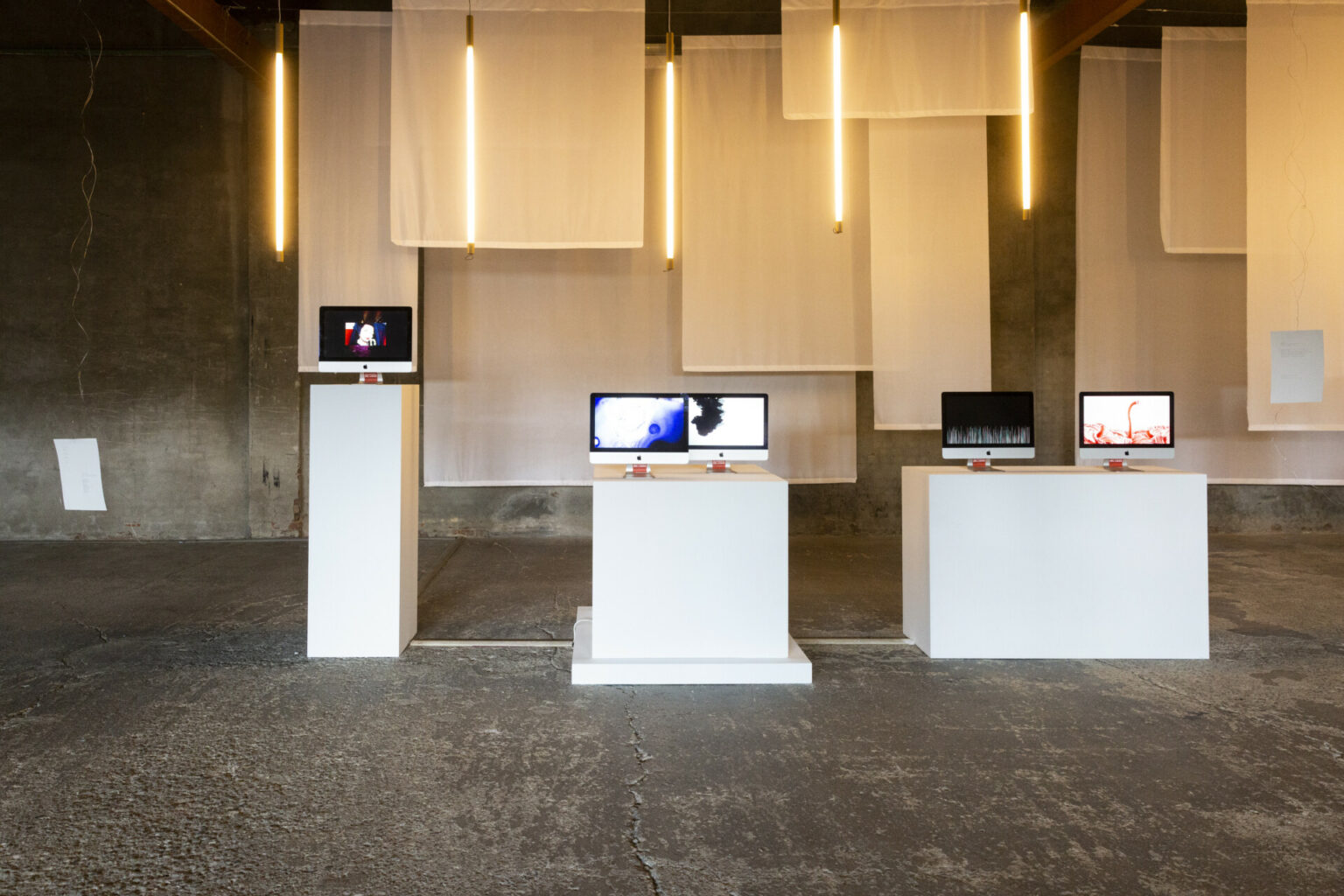 a group of white rectangular tables with computers on it