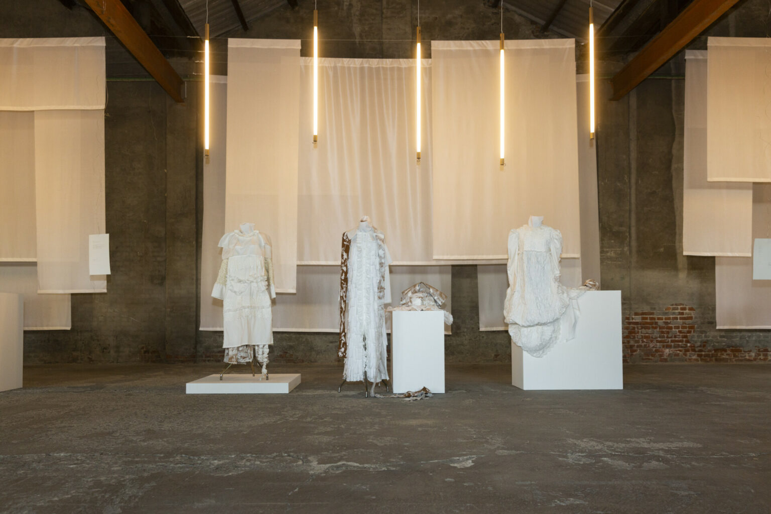 a group of mannequins in a room with white curtains